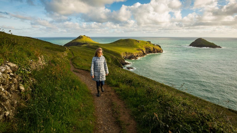 Visitor walking along the coastal path on the Rumps at Pentire, Cornwall